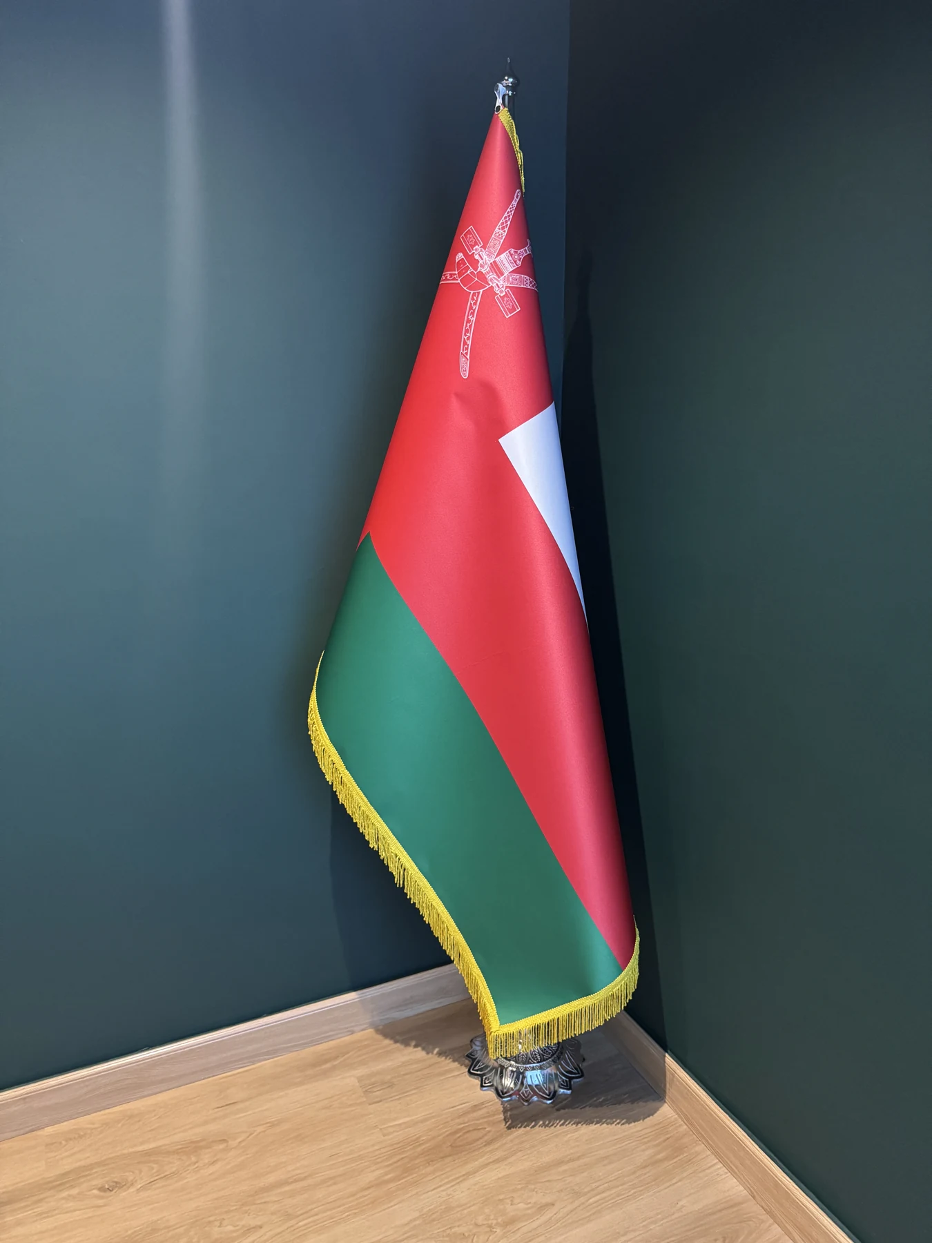 Oman ceremonial flag with gold fringe on a floor stand